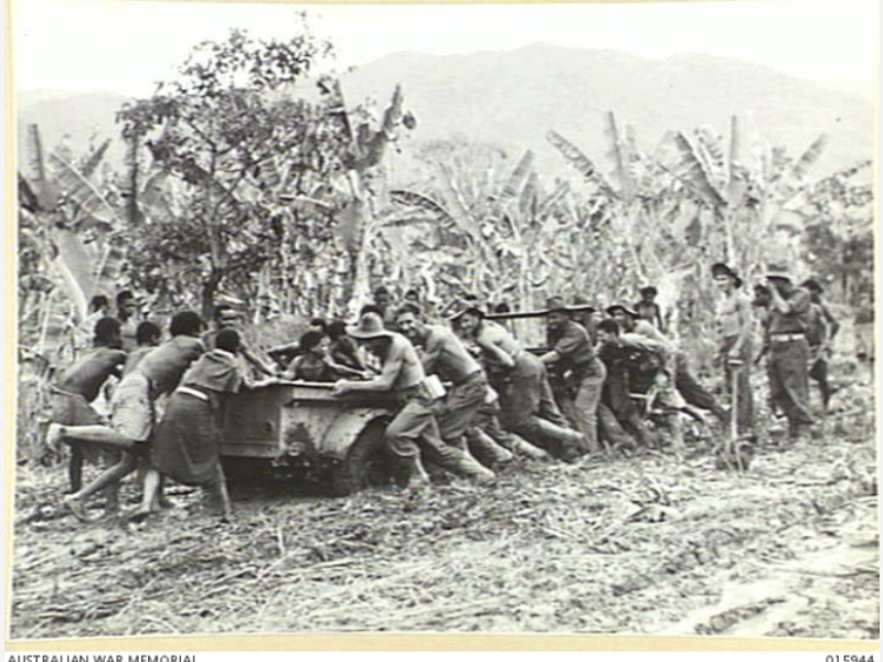 Australian troops and locals pull a jeep out of the mud, near Lae, Papua New Guinea, October 1943. 
