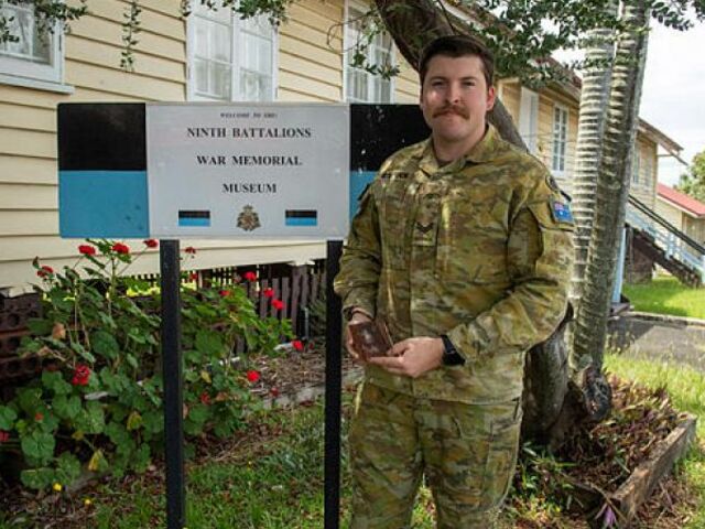 Corporal Jake Bostock with his great grandfather James Dundee Bostock's diary outside the 9th Battalion War Memorial Museum at Gallipoli Barracks, Brisbane