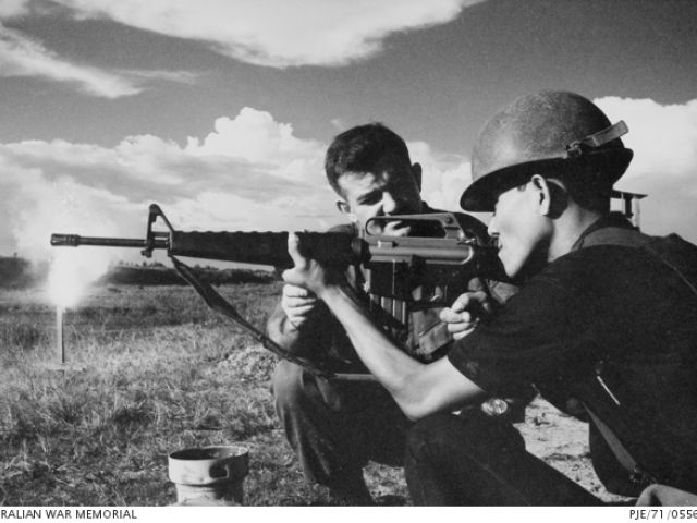 Warrant Officer Class 2 Brian Morrow adjusts a Vietnamese soldier's shooting position. Mekong Delta, South Vietnam. November 1971.