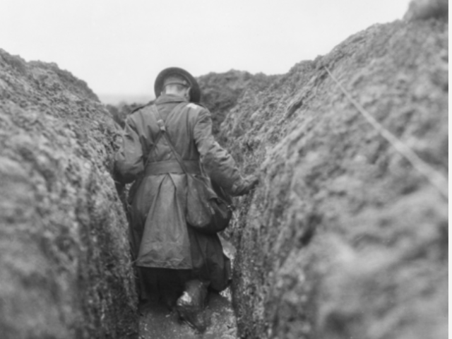 Photo of a soldier wading through the mud in Gird Trench, near Gueudecourt, France, in December 1916.