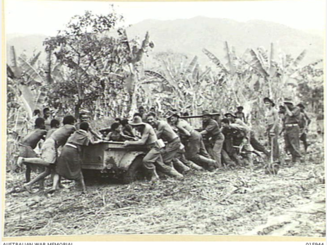Australian troops and locals pull a jeep out of the mud, near Lae, Papua New Guinea, October 1943. 