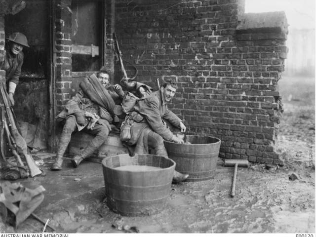Soldiers washing their gum boots outside the gum boot store at Houplines, near Armentieres, Jan 1917