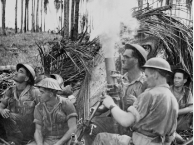 Photograph taken during the final assault on Buna. An Australian mortar crew from headquarters company, 2/12th battalion, lays down a barrage as infantry advances to attack a Japanese pillbox, Giropa Point, Papua, 2 January 1943
