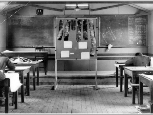 Classroom interior revealing trigonometry, charts and aerial photographs.