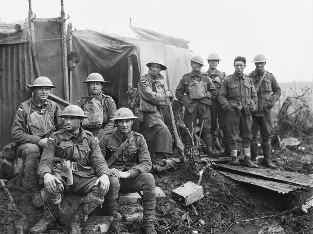 Officers and men of the 8th Battalion take shelter behind a pillbox during an ”area strafe” at Railway Wood in the Ypres Sector. 