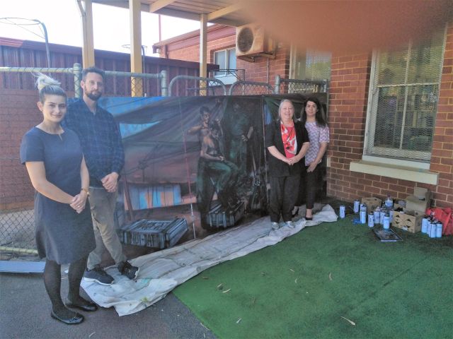 The artist with some of the sponsors of the project in front of the partially completed Nui Dat mural