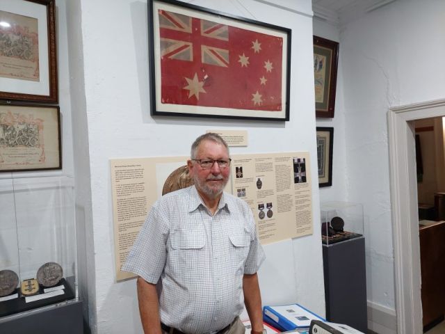 Peter Lacey stands in front of the Gallipoli Flag at the Bega Pioneers’ Museum