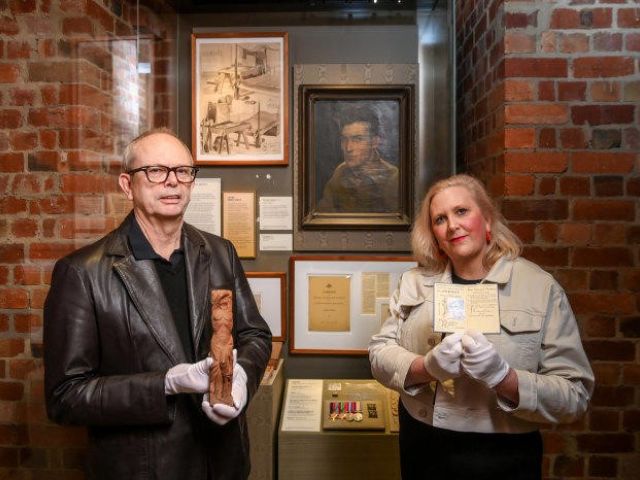 Murray Griffin jnr with the sculpture that artist Murray Griffin carved from a chair leg, and Kate Griffin with his war artist permit