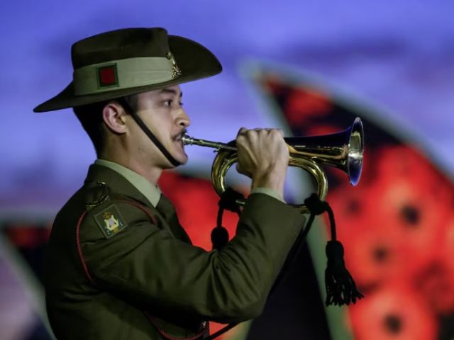 The Sydney Opera House was lit up with poppies as a bugler played on Remembrance Day, 2025. (AAP: Bianca de Marchi)