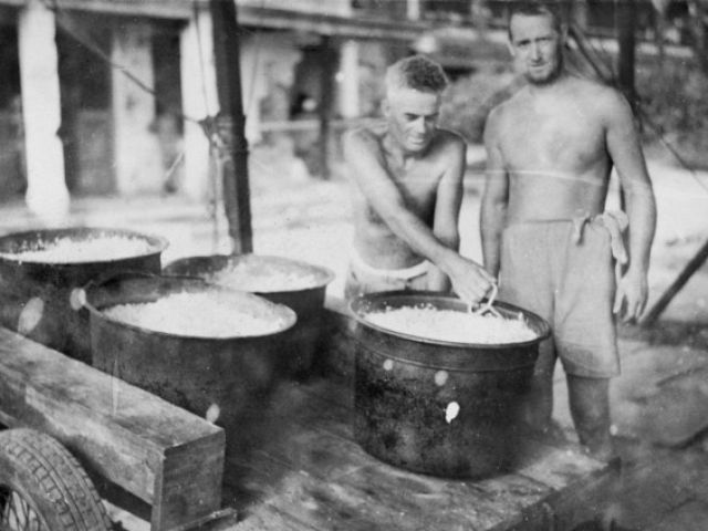 Australian prisoners loading a cart with cooked rice from a camp kitchen, Selarang Barracks, Singapore 1942. Photographer unknown