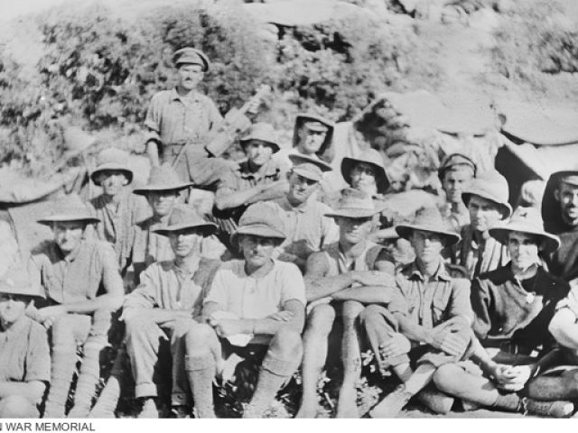 Group portrait of Australian soldiers and officers. Identified is 55 Driver Ernest Sydney Pilcher, 3rd Field Ambulance Brigade, of Pentland, Qld, holding a violin made from a chocolate box. 