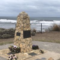 Cairn with ocean in the background. Wreaths are laid at the base.