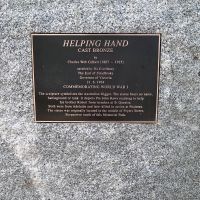 Plaque below statue: 'Helping Hand' by CW Gilbert