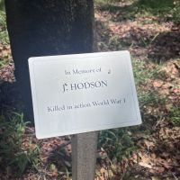 One of many plaques at the base of memorial trees that form a cross leading from the original memorial