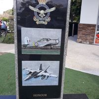 Royal Australian Air Force badge, with two photographs of planes, "Honour" written at base of monument